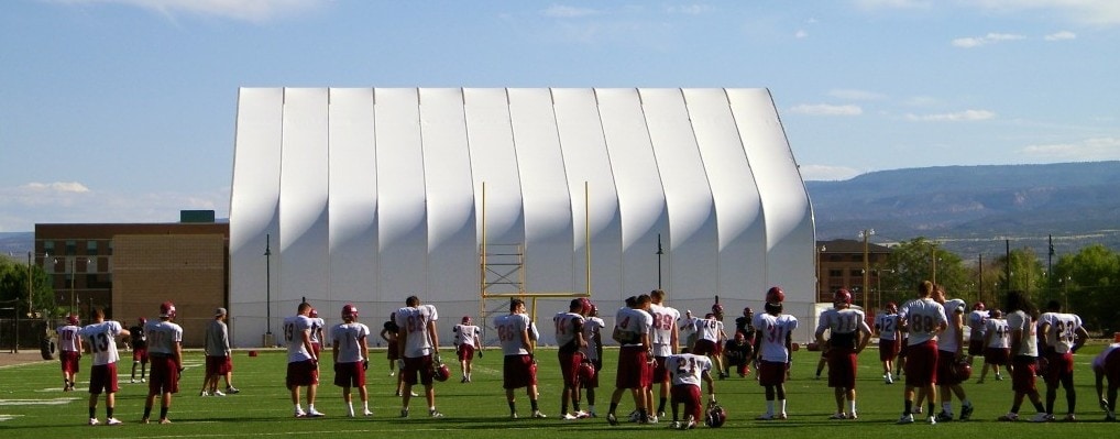 fabric structure behind football players practicing outside