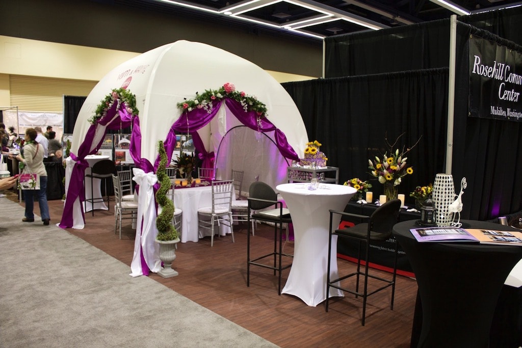 Customizing a WeatherPort Canopy as seen at the 2015 Seattle Wedding Show is as easy as adding flowers, lighting, and colored fabrics and bows.