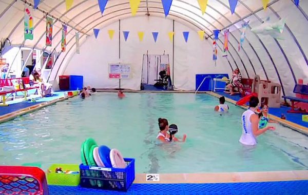 Kids learning to swim in a fabric enclosed pool