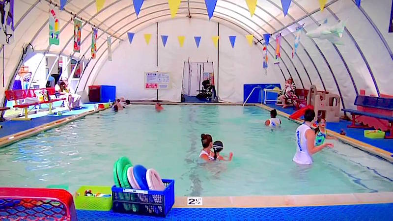 Kids learning to swim in a fabric enclosed pool