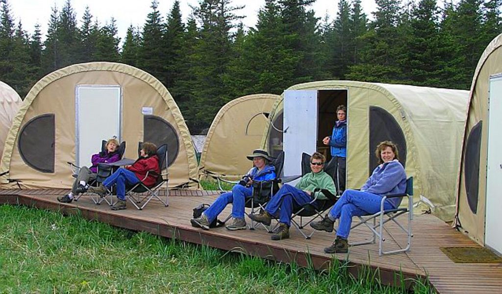 people relaxing outside individual fabric tents