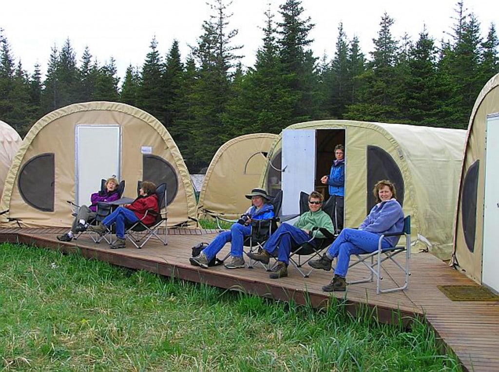 people relaxing outside individual fabric tents