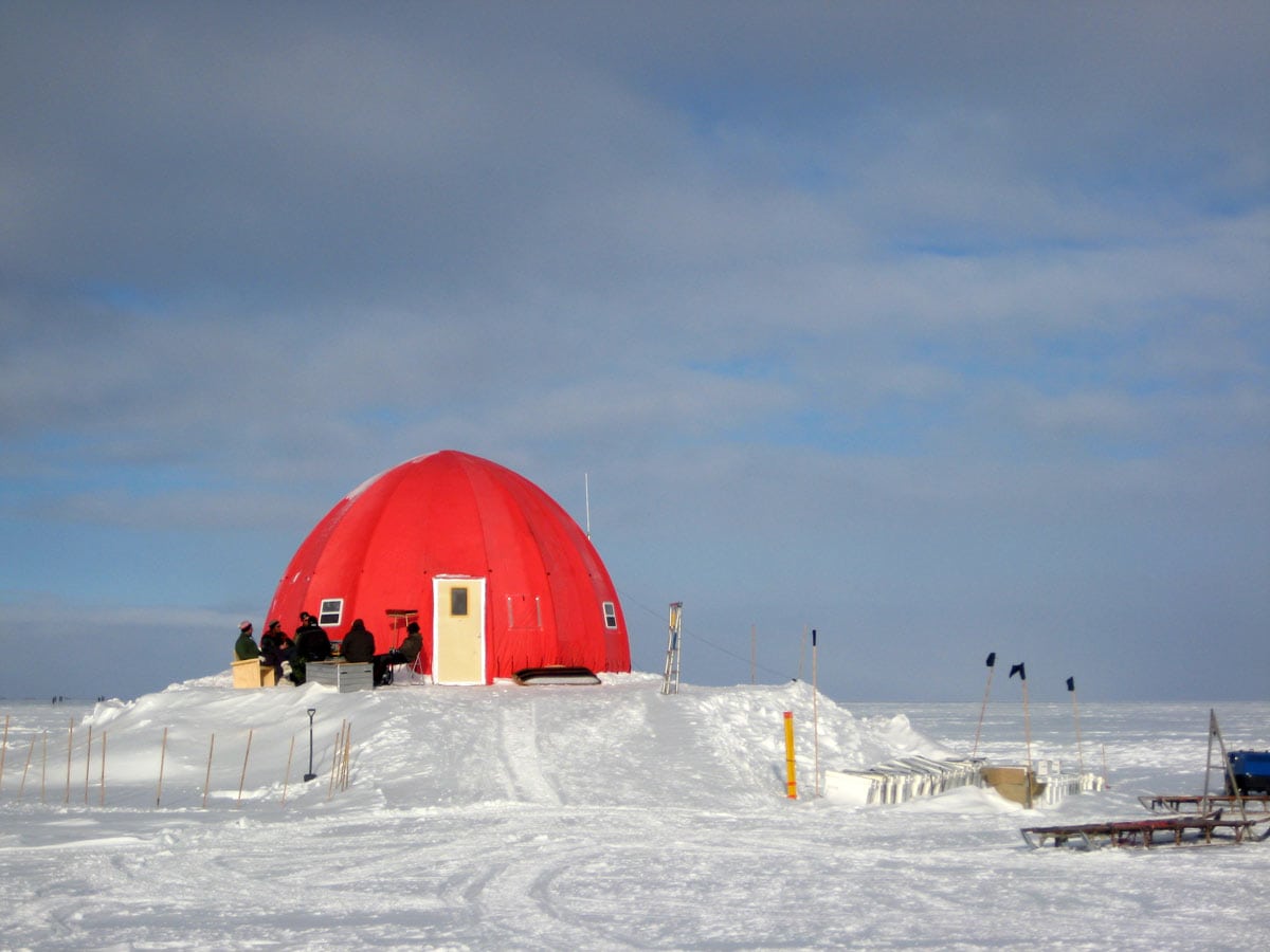 single dome structure in snow with hikers in front