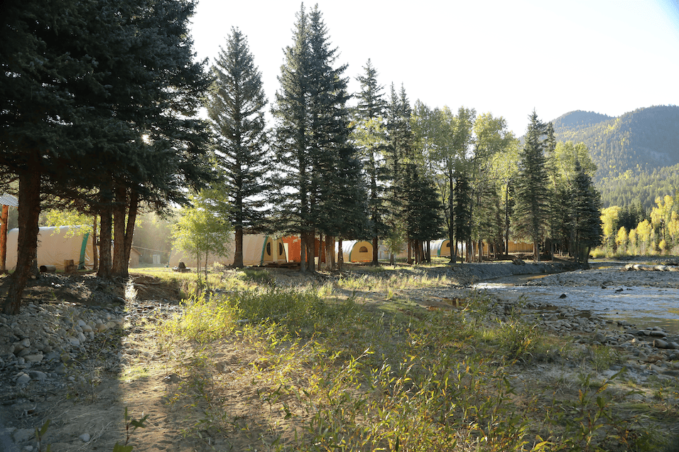 weatherport cabins in wooded campground before sunset