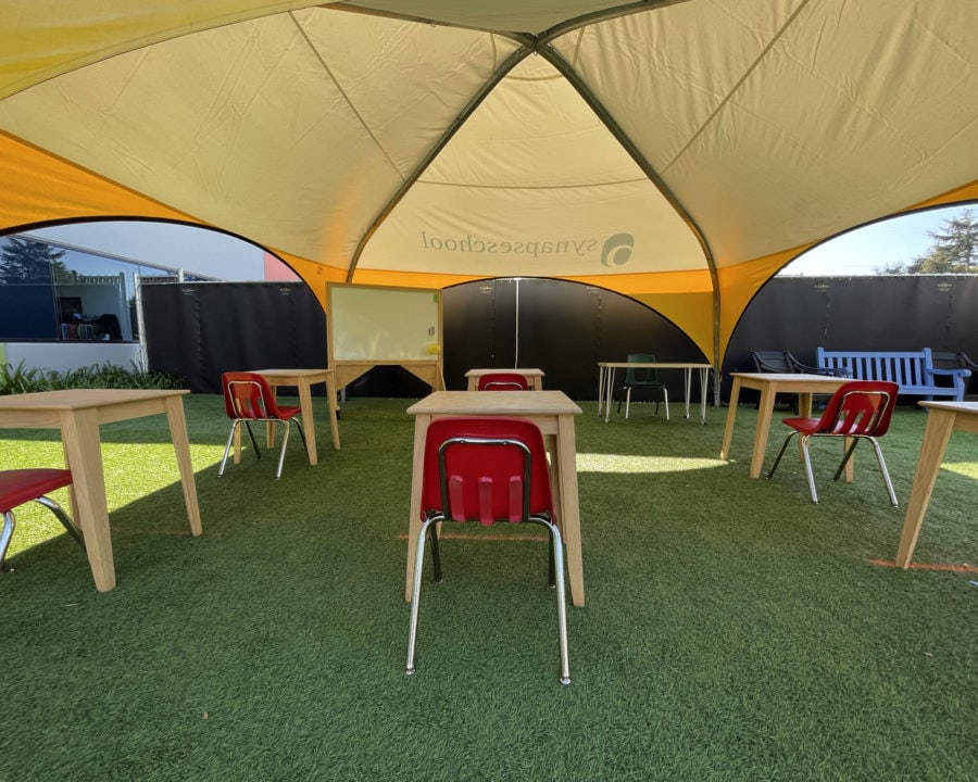 student desks set up in fabric structure for outdoor class