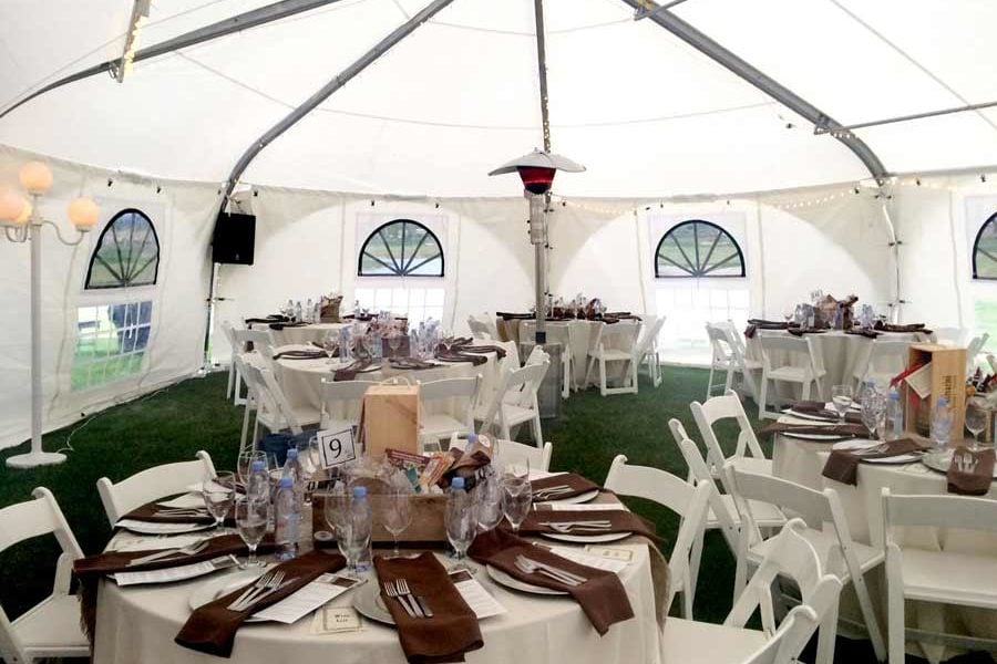 Wedding tent with tables and chairs set up.