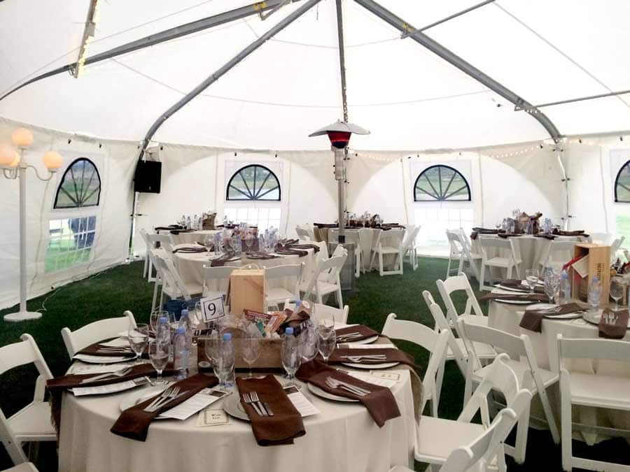 Wedding tent with tables and chairs set up.